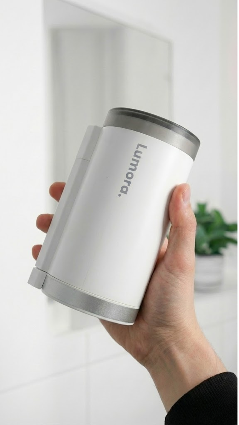 Close-up van de witte Lumora mini beamer die in één hand wordt vastgehouden om het compacte en draagbare formaat te tonen.