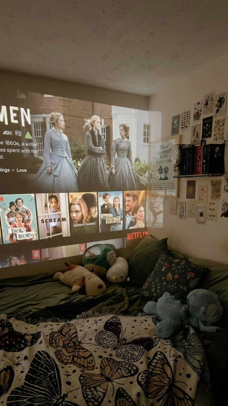Een gezellige slaapkamer waar de Lumora beamer een Netflix-menu en film direct op de muur boven het bed projecteert.